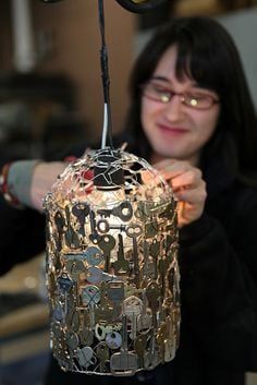 a woman holding up a lamp made out of metal parts