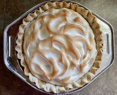 a pie sitting on top of a metal pan covered in white frosted icing