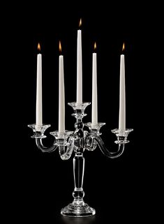 a group of lit candles sitting on top of a glass candle holder in front of a black background