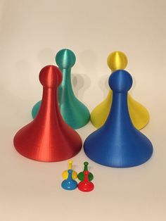 three different colored pawns sitting next to each other on a white surface with small toys around them