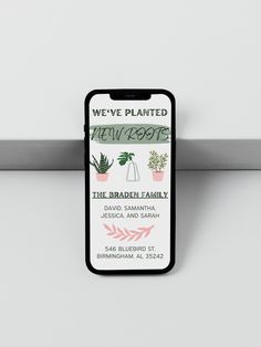 a business card attached to a metal hook on a white wall with pink and green plants