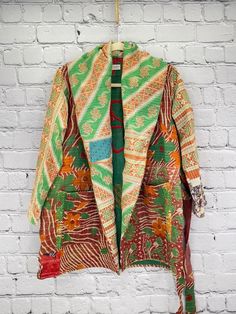 Our gorgeous coats are made from fine kantha embroidered cotton. This is a lightweight coat with an oversized collar, large pockets and a self-tie belt. Kantha coats are a “one size” style that measures approximately 37” in length, sleeve length 25”, shoulder to shoulder 19” and armpit to armpit, 28”. Recommended up to size 18. Care Instructions: Dry clean or hand wash and line dry for longest life. Disclaimer: The material used in this style is repurposed, vintage material. Small imperfections Cotton Long Sleeve Robe For Winter, Long Green Cotton Outerwear, Embroidered Winter Outerwear With Kimono Sleeves, Traditional Long Coat For Spring, Long Sleeve Robe For Fall Festival, Vintage Long Sleeve Robe For Fall, Long Sleeve Green Robe For Fall, Patchwork Kimono Sleeve Outerwear For Festival, Winter Outerwear With Patchwork And Kimono Sleeves