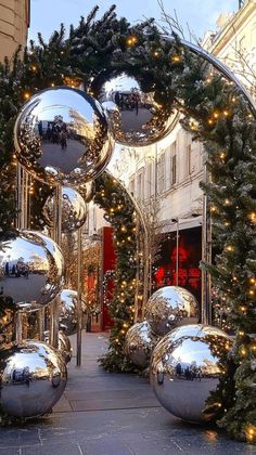 the entrance to a building decorated with christmas trees and large silver balls in front of it