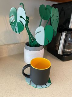 a coffee cup sitting on top of a kitchen counter next to a potted plant