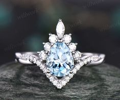 an engagement ring with a blue topazte surrounded by white diamonds on a rock