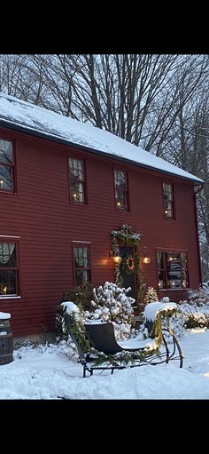 a red house is covered in snow and christmas lights are on the windows, along with a sleigh