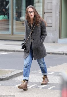 a woman walking across a street wearing glasses