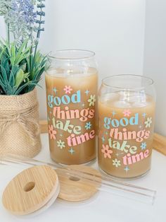 two candles sitting on top of a table next to a potted plant and coaster