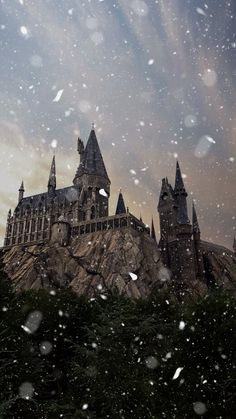 the hogwarts castle is covered in snow as it sits on top of a hill