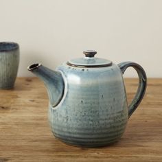 a teapot and two cups on a wooden table