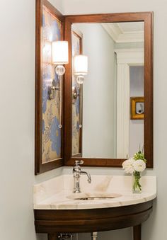 a bathroom sink sitting under a mirror next to a wall mounted faucet with lights on it