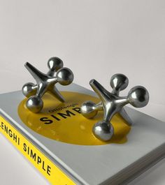 two silver metal objects sitting on top of a yellow and white book cover with the title, simple