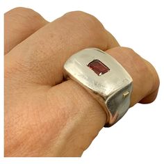 Bold, modern, sculptural, chunky garnet and sterling silver signet statement ring by Lebanese designer Rosa Maria. Marks: Rosa Maria, 925 for Sterling Silver Size: 8.5 Weight: 29.8 grams Condition: Very Good, light surface wear, nice patina Ring Face: 22mm by 15mm Garnet: 6mm by 4mm, emerald cut, lively burgundy Provenance: from the collection of a noted NYC psychiatrist and collector of unusual, often one-of-a-kind jewels. This sophisticated, modern Rosa Maria signet ring centers an emerald cut garnet framed by industrial, slightly rough, substantial sterling silver surround. The organically shaped chunky band feels like it was custom made for your finger. A striking, edgy take on the classic signet motif. Rosa Maria jewelry by Rosy Abourous is a Lebanese avant-garde, fashion-forward bran Chunky Statement Ring, Chunky Silver Rings, European Jewelry, Unusual Rings, Silver Horse, Modernist Jewelry, Gold Ring Designs, Silver Signet Ring, Gold Signet Ring