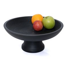 two apples and an orange sit on a black plate with a white background in the center