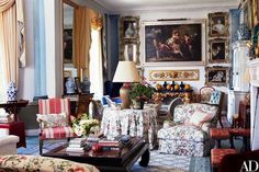 a living room filled with lots of furniture and paintings on the wall above it's fireplace