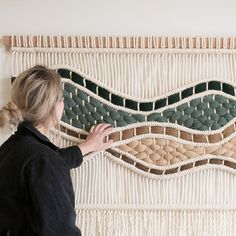 a woman is working on a wall hanging