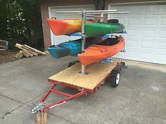 three kayaks on a cart in front of a house