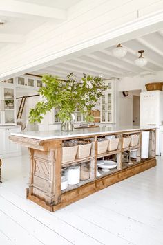 a kitchen with white walls and wooden flooring is pictured in this image, there are chairs around the island