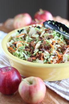 a yellow bowl filled with salad next to apples