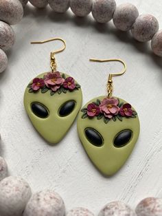 a pair of green alien earrings with pink flowers on them