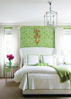 a bedroom with green wallpaper and white bedding