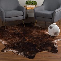 two chairs and a table with a vase on it in front of a cowhide rug