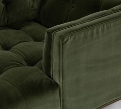 a green velvet couch sitting on top of a white floor