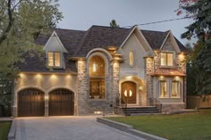 a large house with two garages and lights on