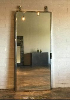 a large mirror sitting on top of a wooden floor next to a white brick wall