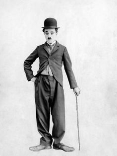 a black and white photo of a man in a top hat holding a cane with his hands on his hips