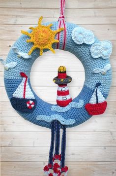 a crocheted wreath with a sailboat and lighthouse on it hanging from a wooden wall