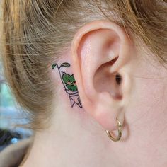 Sharing with you another Legend of Zelda-themed tattoo -- this time done by @thistlekae!! This little korok piece as an ear ornament is so cute!⁠ ⁠ "Ya ha ha! You found me!⁠ ⁠ In love with this wee korok peeking out from behind Nicole's ear. Thanks for the trust!⁠ ⁠ And a plug for Nicole - if you are in need of Thai or regular massage, hit her up nicolejangula.rmt 🤩" - Kathleen⁠ Breathe Of The Wild Tattoo, Korok Tattoo Wind Waker, Tattoo Ideas Zelda, Zelda Dragon Tattoo, Breath Of The Wild Tattoo, Zelda Ocarina Of Time Tattoo, Korok Tattoo, Zelda Tattoo Ideas