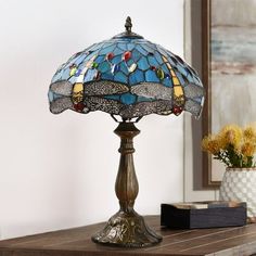 a table lamp sitting on top of a wooden table next to a vase with flowers