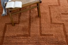 an open book sitting on top of a wooden bench in front of a brown rug