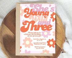 a pink and orange birthday card with flowers on it sitting on top of a wooden plate