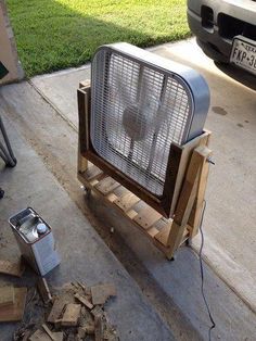 a metal fan sitting on top of a wooden cart next to a pile of wood