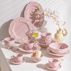 pink dishes and cups are arranged on a table