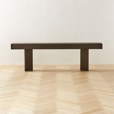 a bench sitting on top of a hard wood floor next to a white wall in an empty room