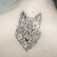 the back of a woman's shoulder with flowers and a fox tattoo