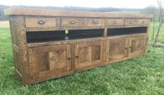 an old wooden entertainment center with drawers and knobs on the doors is sitting in some grass