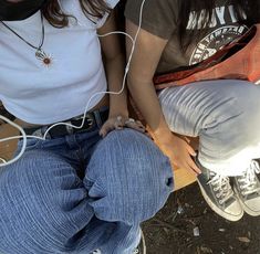 two people sitting next to each other with headphones in their ears and one holding onto the back of another person's leg