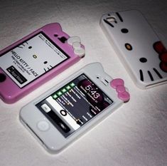 two hello kitty cell phones sitting on top of a white table next to each other