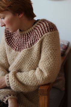 a woman sitting in a chair wearing a sweater