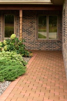 a red fire hydrant sitting on the side of a brick building next to green plants