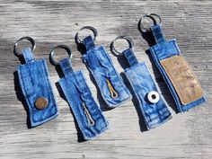 four pairs of blue jeans with metal handles and key chains hanging from them on a wooden surface