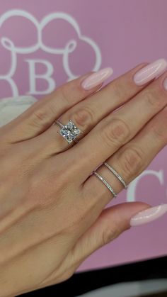 a woman's hand with two rings on her fingers and a diamond ring in the middle