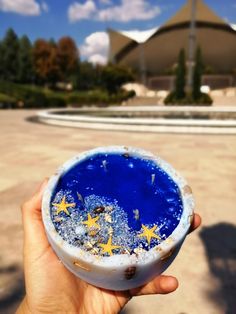 a person holding up a blue bowl with yellow stars on it in front of a building