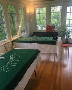 two beds in a room with wooden floors and green sheets on them, along with windows