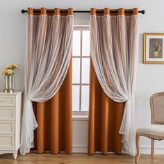 an orange and white curtain hanging in front of a window with a chair next to it