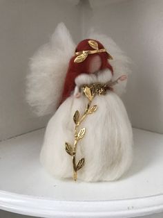 a white and red santa claus doll with gold accents on it's head sitting in a shelf